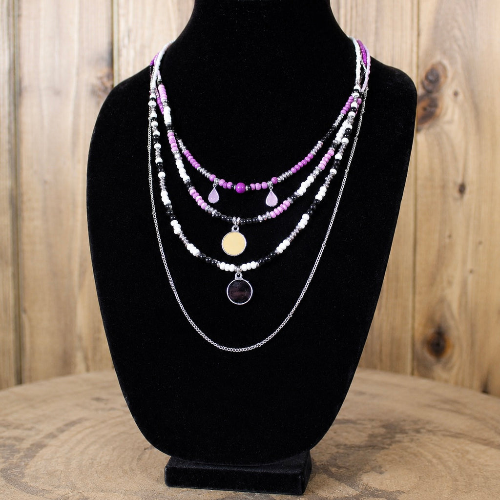 Layered beaded necklace with silver chains, magenta beads, and round pendant charms