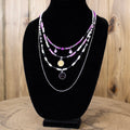 Layered beaded necklace with silver chains, magenta beads, and round pendant charms