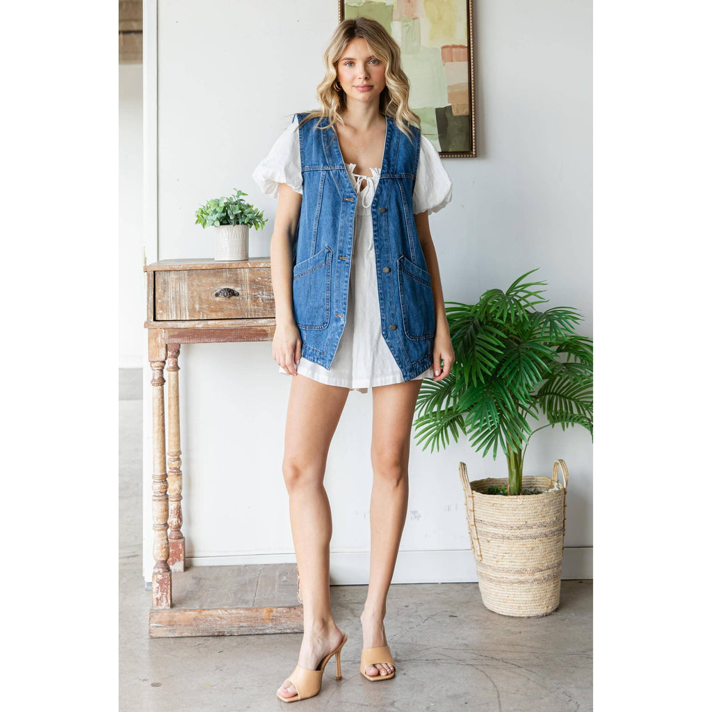 Sleeveless denim vest with button front and patch pockets, worn over a dress