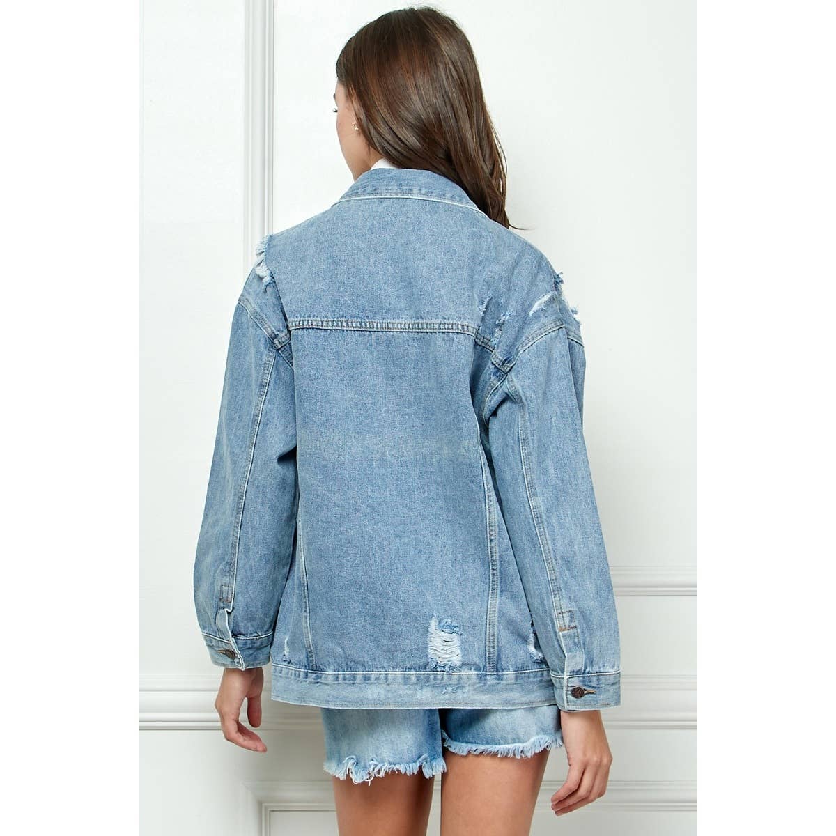 Medium-wash distressed denim jacket from back view with buttoned yoke and pockets