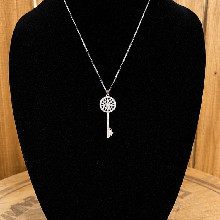 Silver-tone key necklace with round crystal medallion and dangling key charm