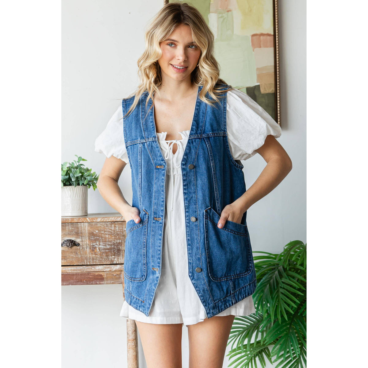 Denim vest with button closures and front patch pockets over a white dress