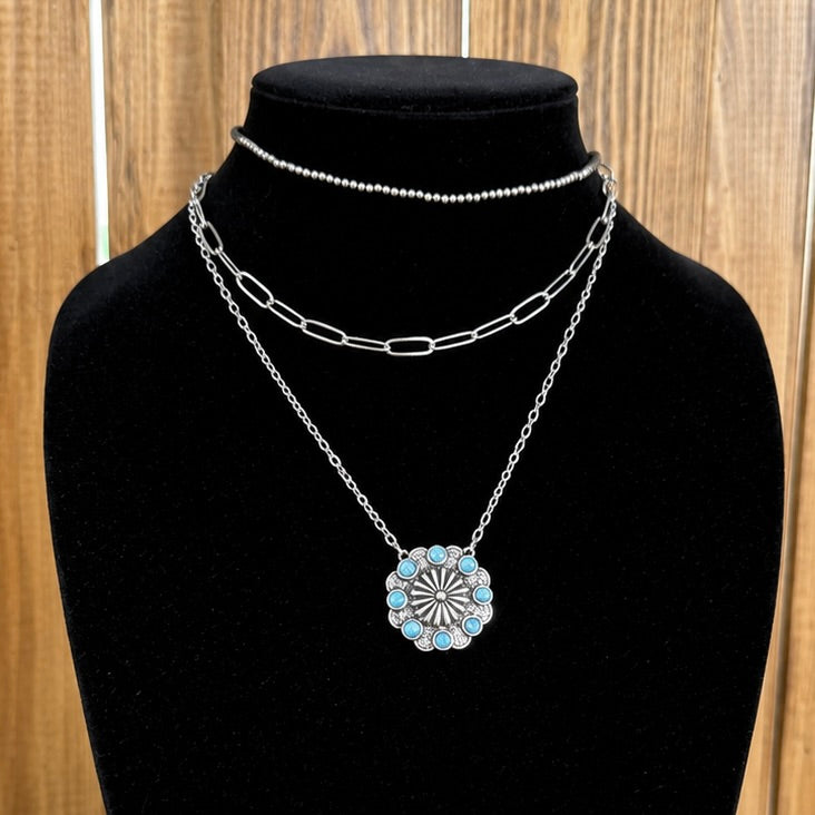 Layered western necklace with silver chains and turquoise oval flower pendant