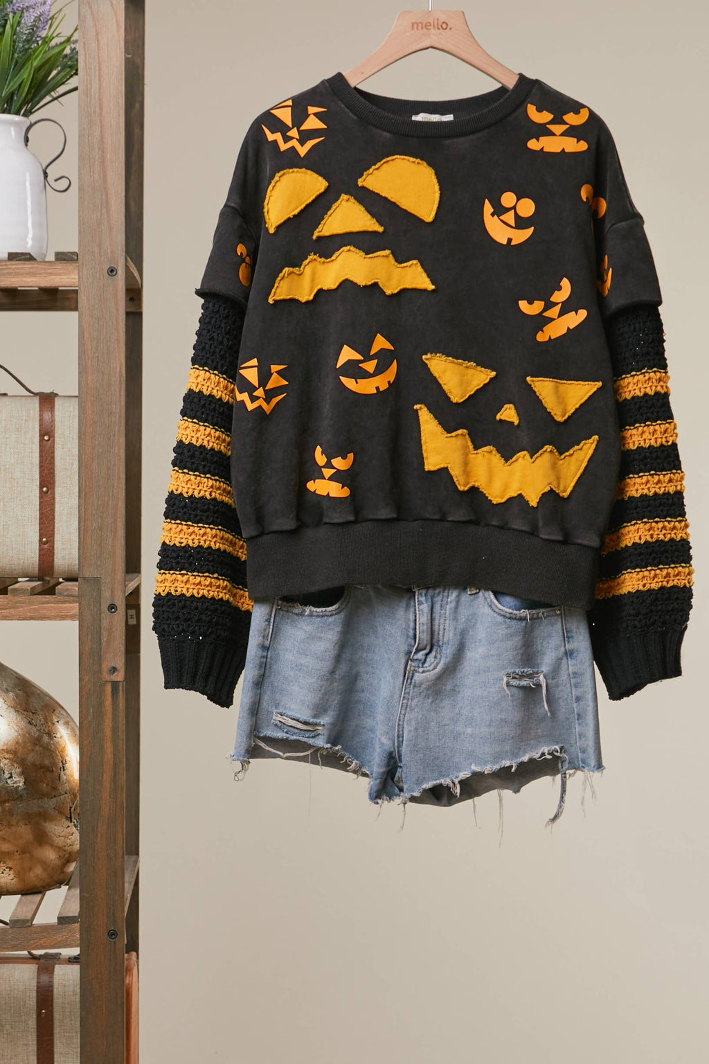 Black knit top with orange Halloween graphics and striped sleeve cuffs