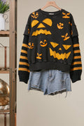 Black knit top with orange Halloween graphics and striped sleeve cuffs