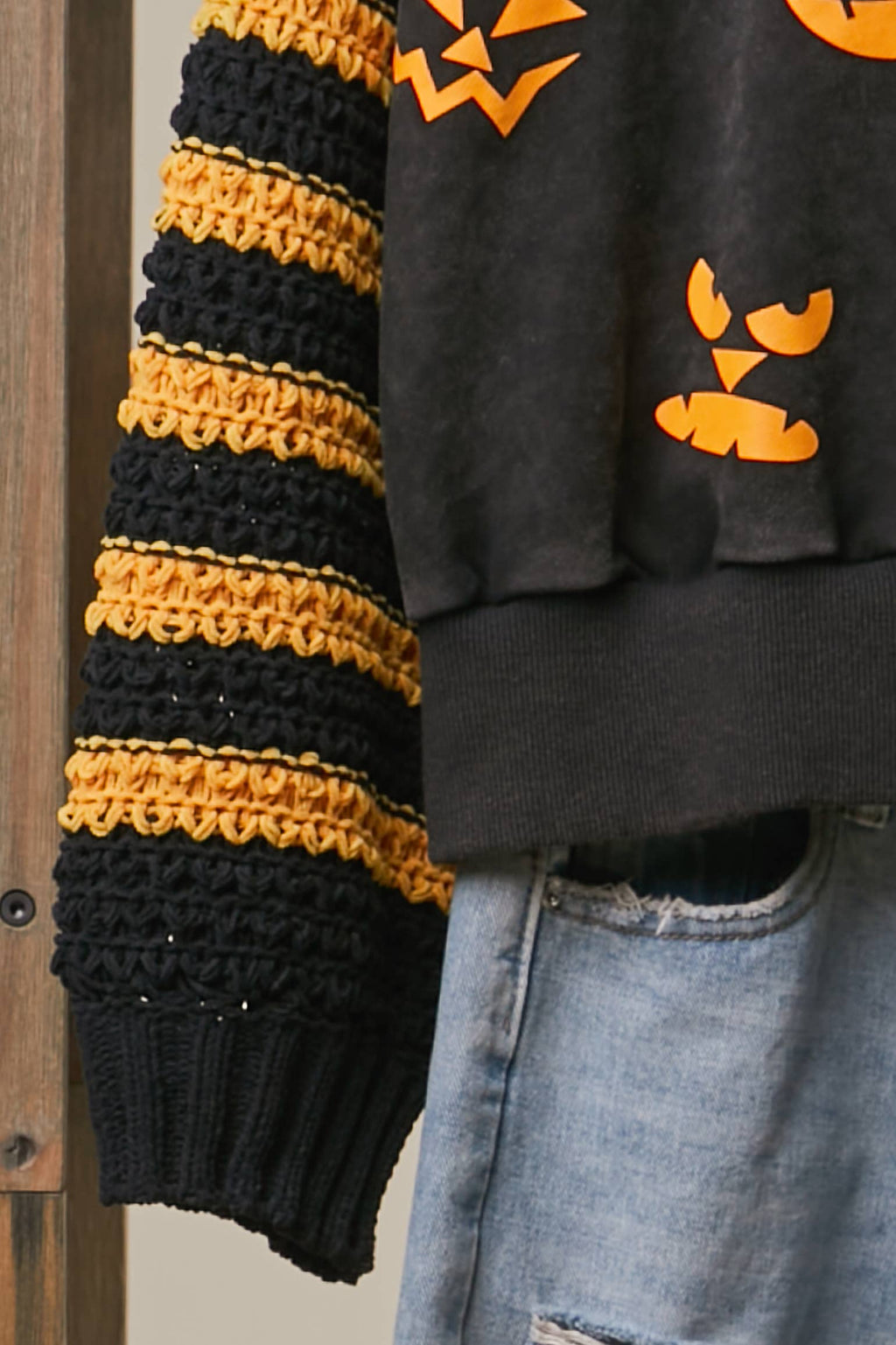 Black knit top with yellow-and-black striped sleeve and ribbed hem
