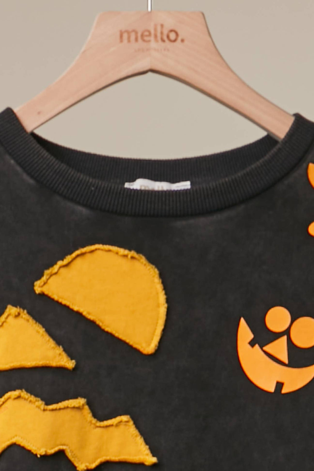 Black top neckline with orange pumpkin graphic, ribbed collar