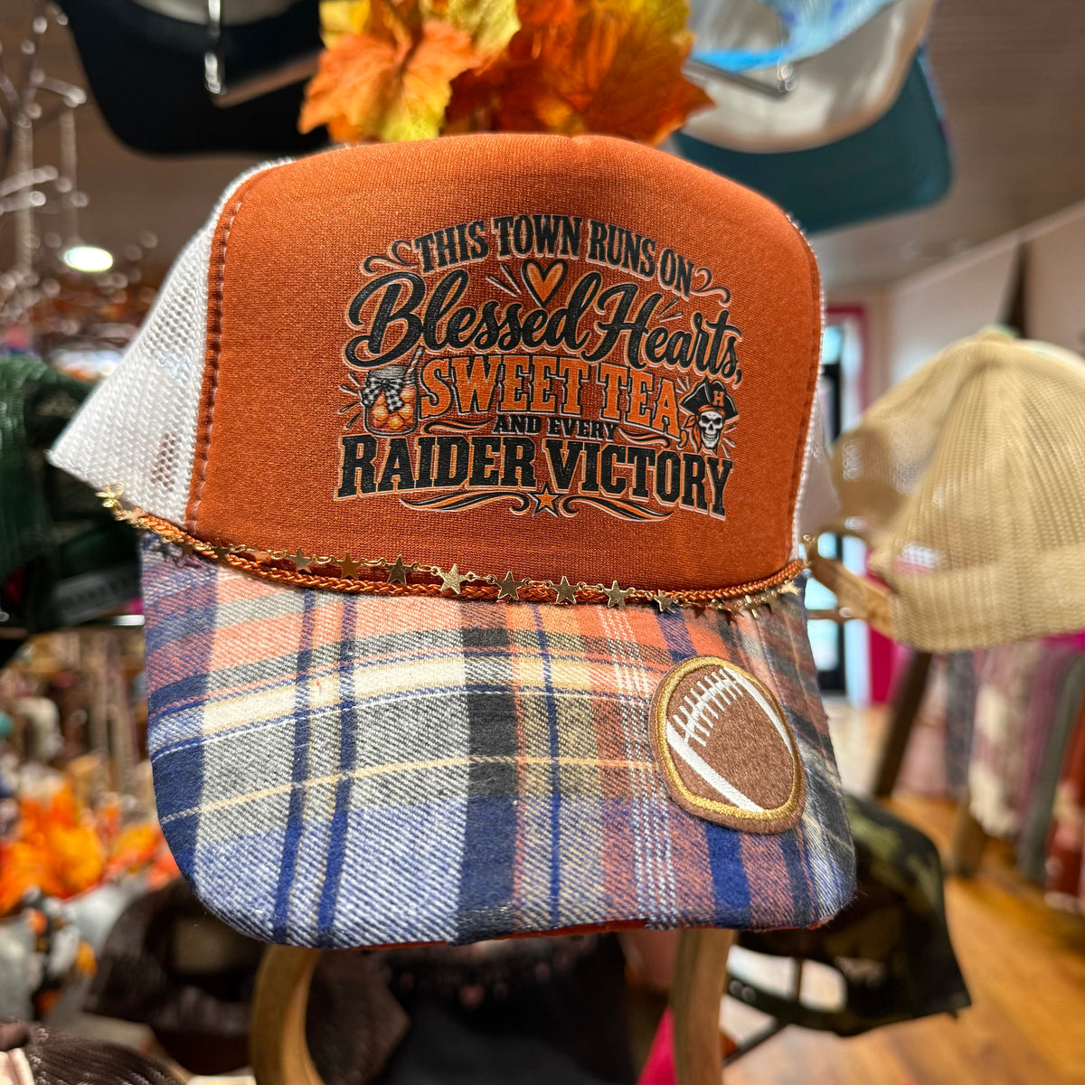Embroidered trucker cap with orange front panel and blue plaid brim, mesh sides