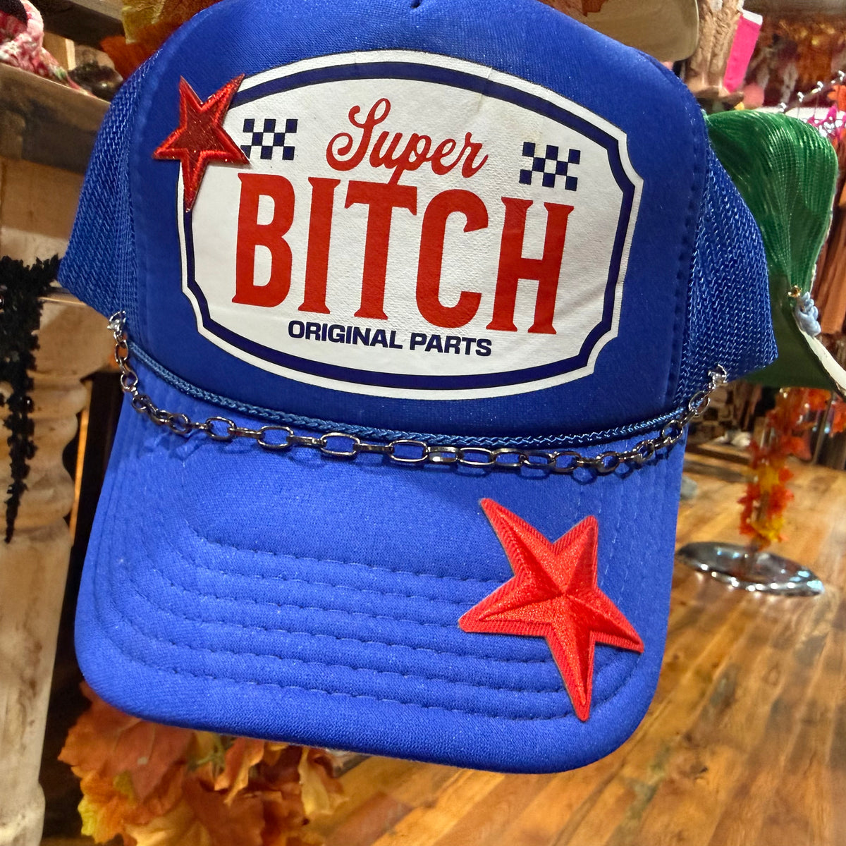 Blue baseball cap with oval 'Super BITCH' patch and red star accents