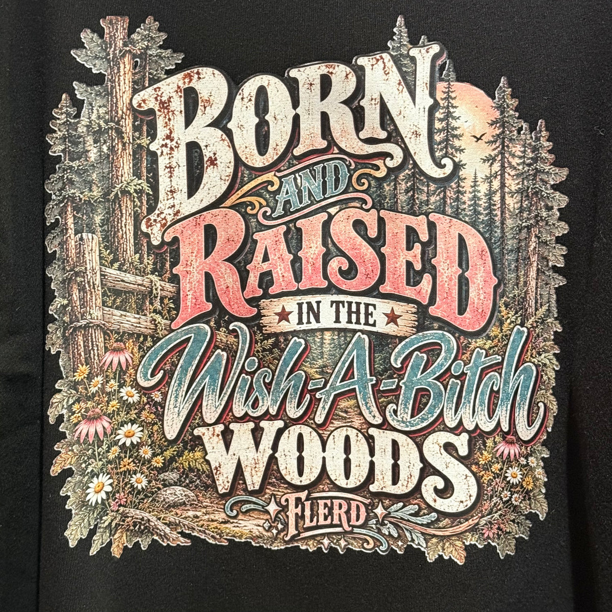 Black sweatshirt front close-up with distressed lettering and woodland illustration