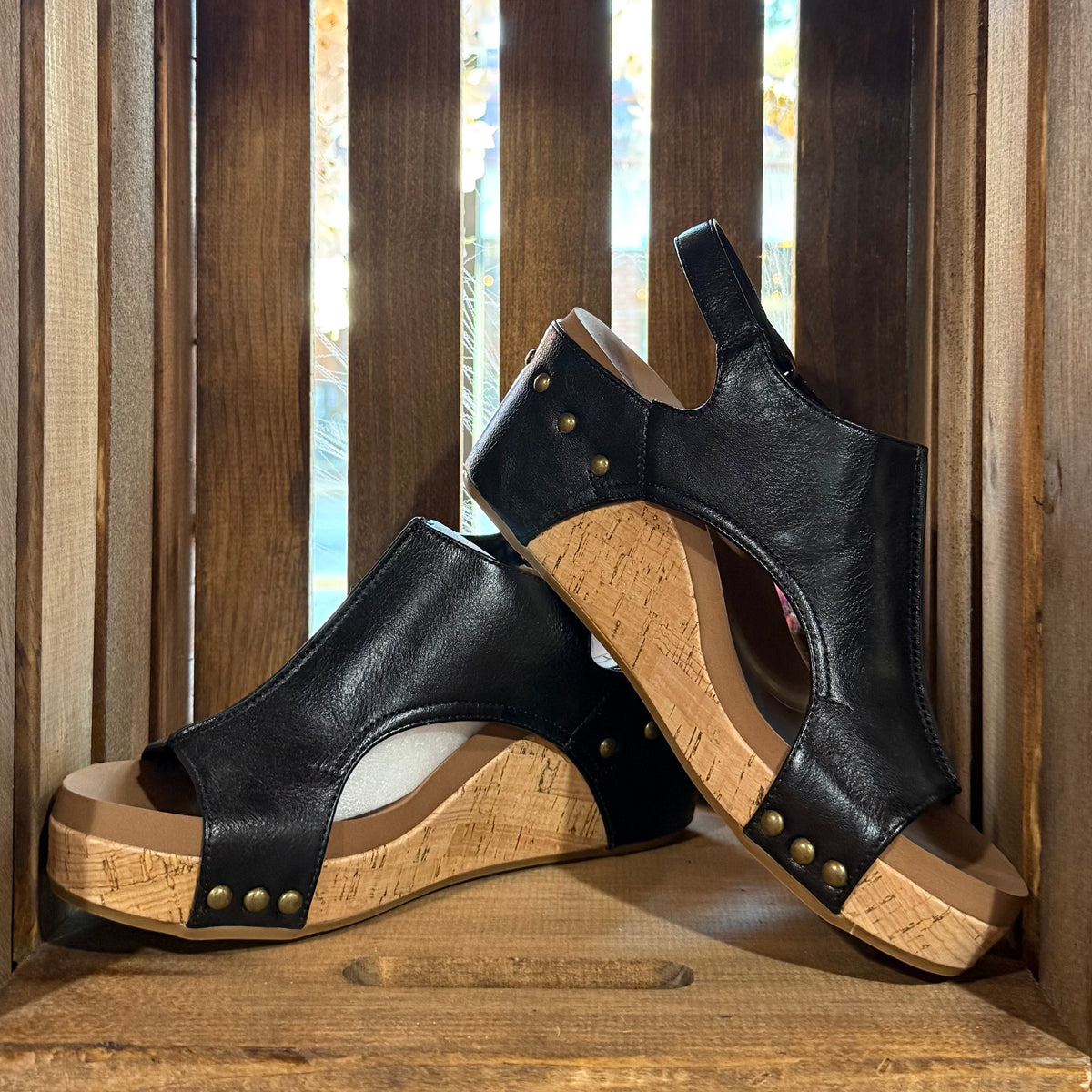 Black heeled sandal with open toe, stud trim, cork-textured wedge sole.
