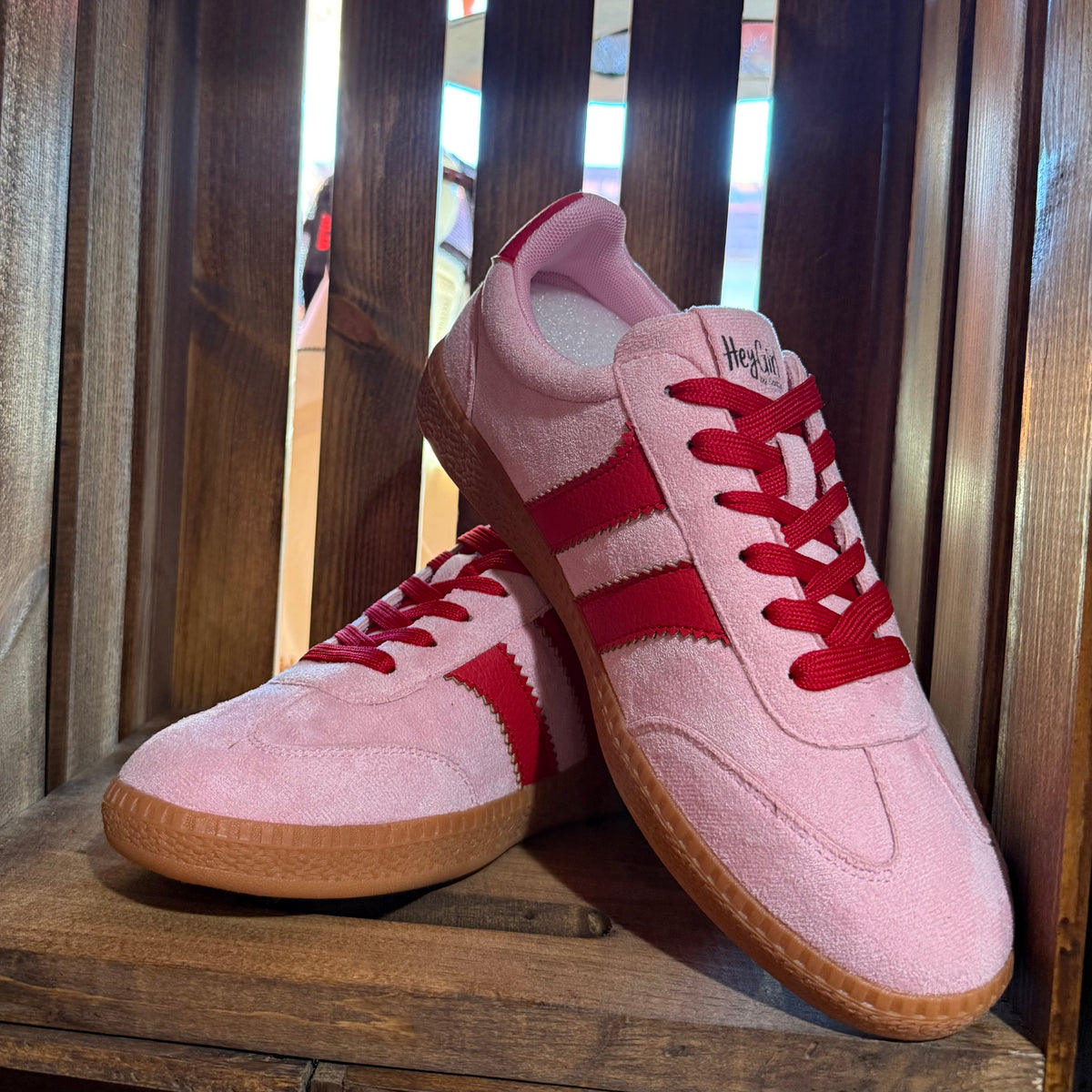 Pink suede lace-up sneakers with red side stripes and gum sole