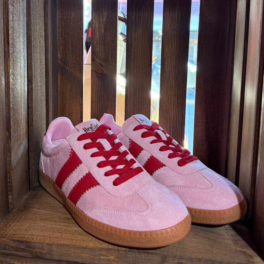 Pink suede low-top sneakers with red-striped sides and lace-up design, gum sole