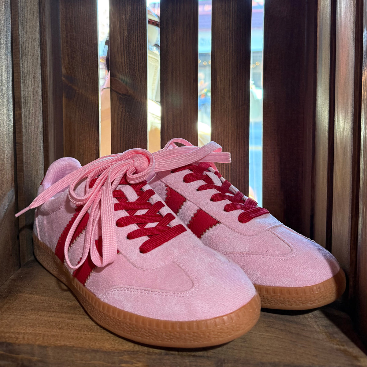 Pink suede sneakers with red stripe accents, lace-up front and gum sole