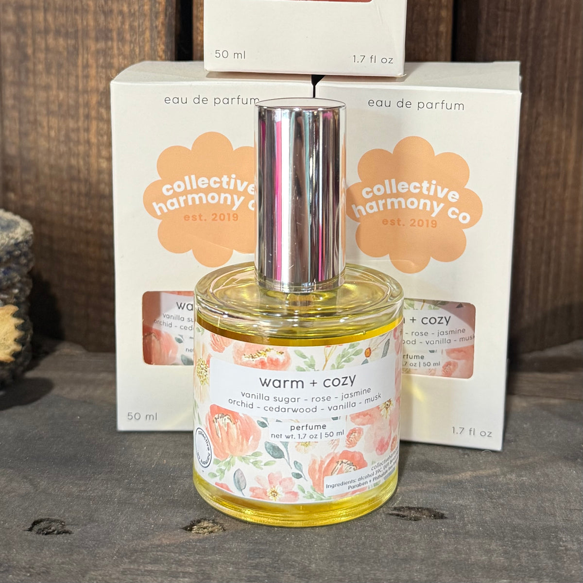 Warm + Cozy eau de parfum bottle, gold cap, floral label, 50 ml