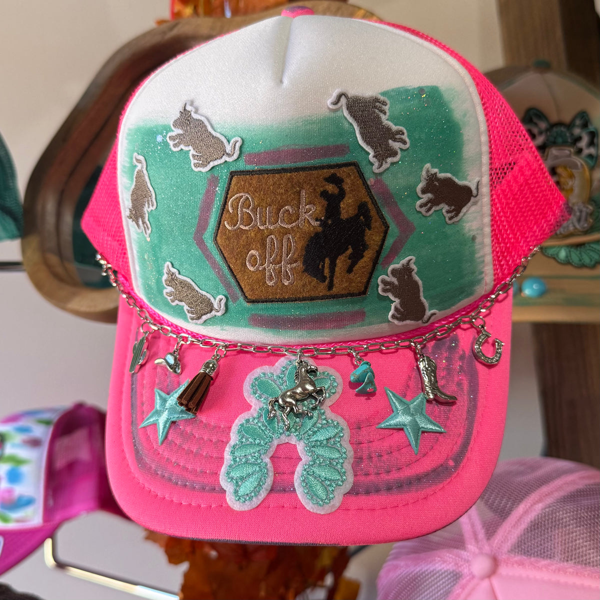Pink trucker hat with front logo patch and buck silhouettes, star and bead charm details