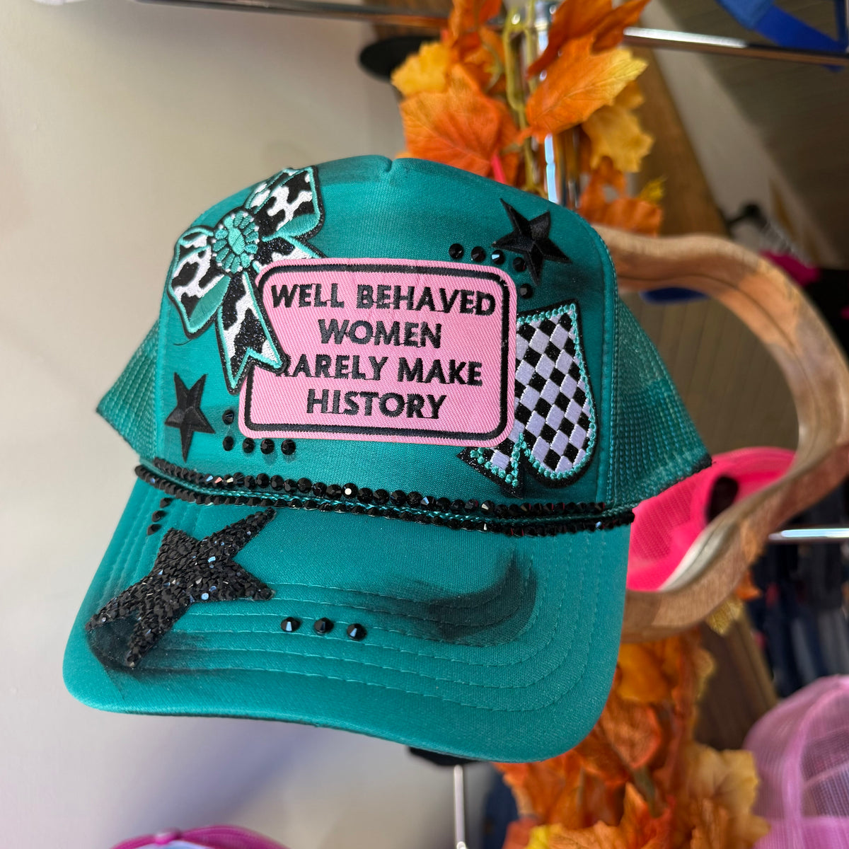Teal trucker cap with front text patch and black star applique, mesh back