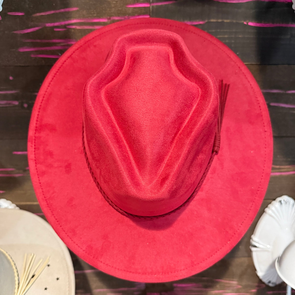 Red arrow-shaped suede hat with wide brim and stitched peaked crown
