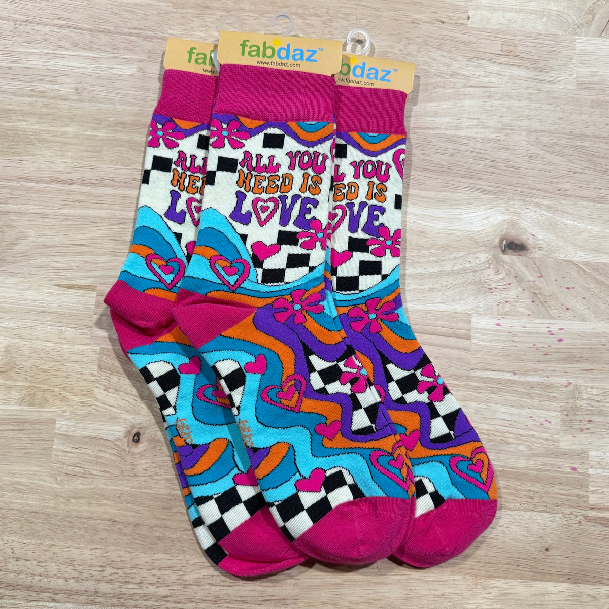 Funny socks with rainbow hearts, checkered blocks, and stripes on purple, blue, and pink.