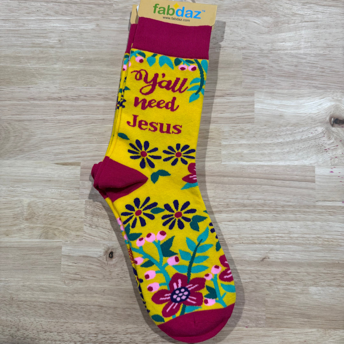 Funny socks with yellow floral print, 'You Need Jesus' text, and burgundy cuffs.