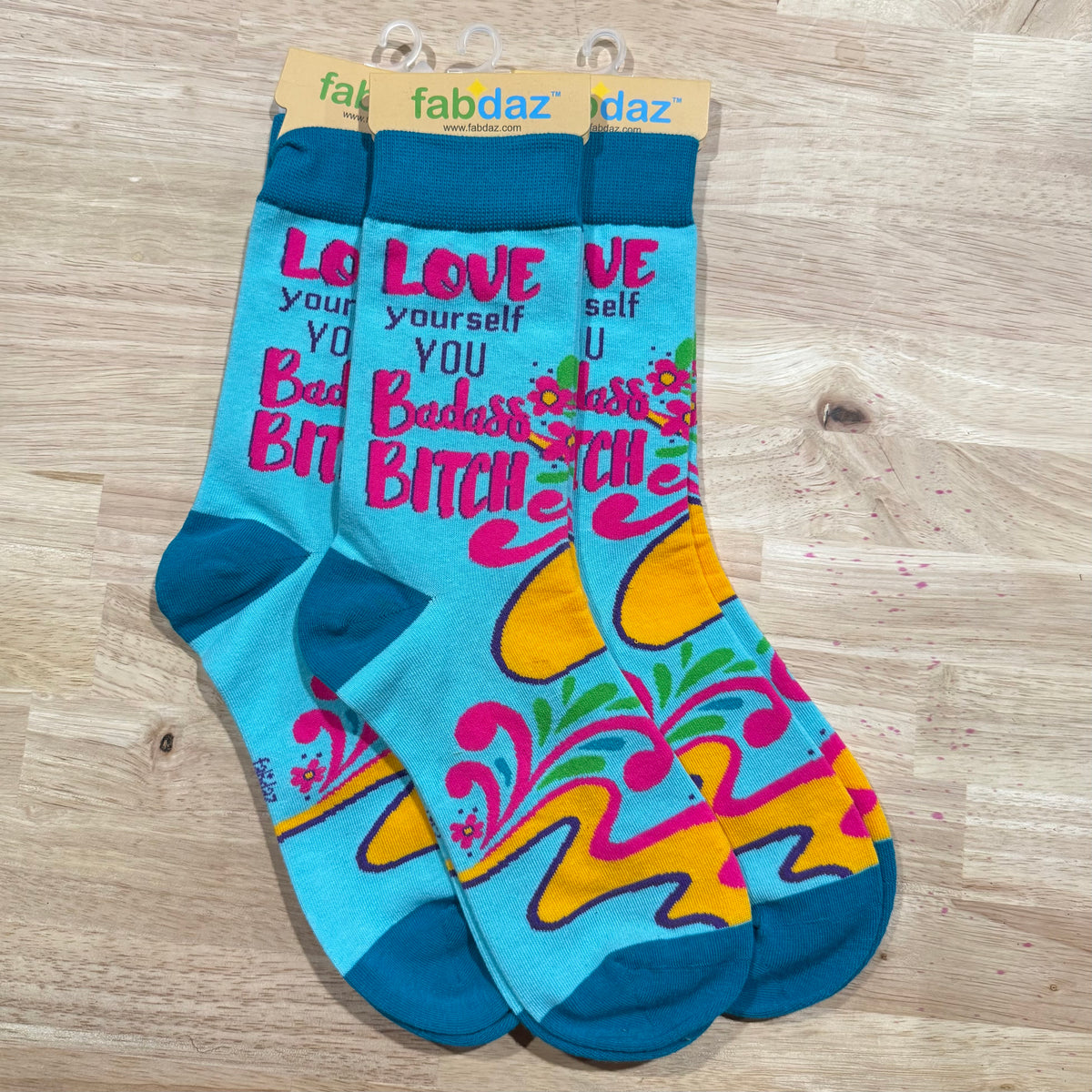 Blue crew socks with “LOVE YOURSELF” and “BADDEST BITCH” text plus floral accents