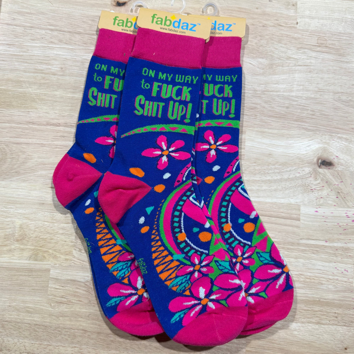 Blue and magenta crew socks with profanity text and colorful floral and paisley designs