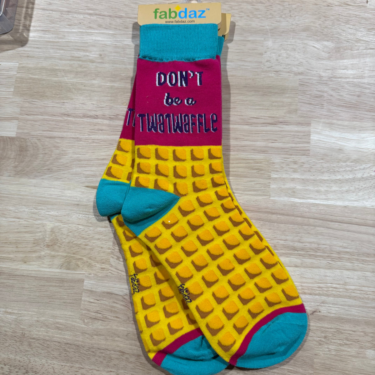 Yellow waffle-pattern adult novelty socks with maroon “DON’T be a Twatwaffle” text