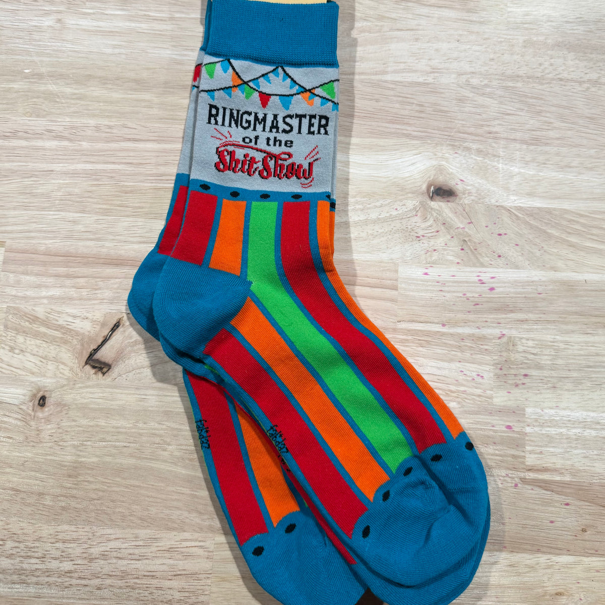 Blue adult novelty socks with rainbow stripes and “Ringmaster of the Shirt Show” lettering