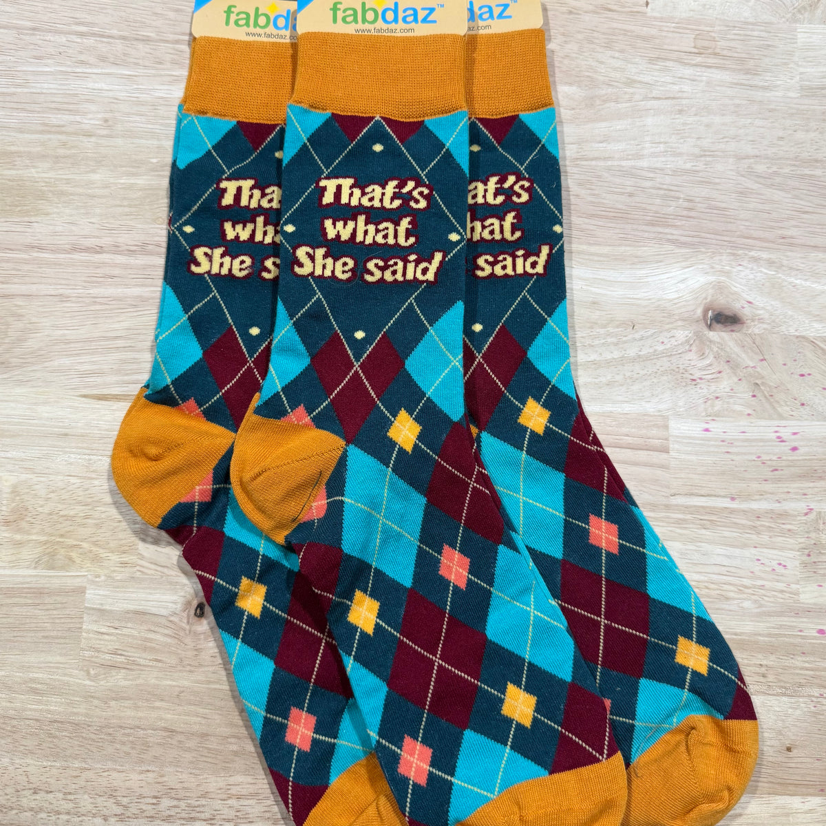 Funny socks with teal and maroon plaid, mustard cuffs, and text 'That's what she said'.