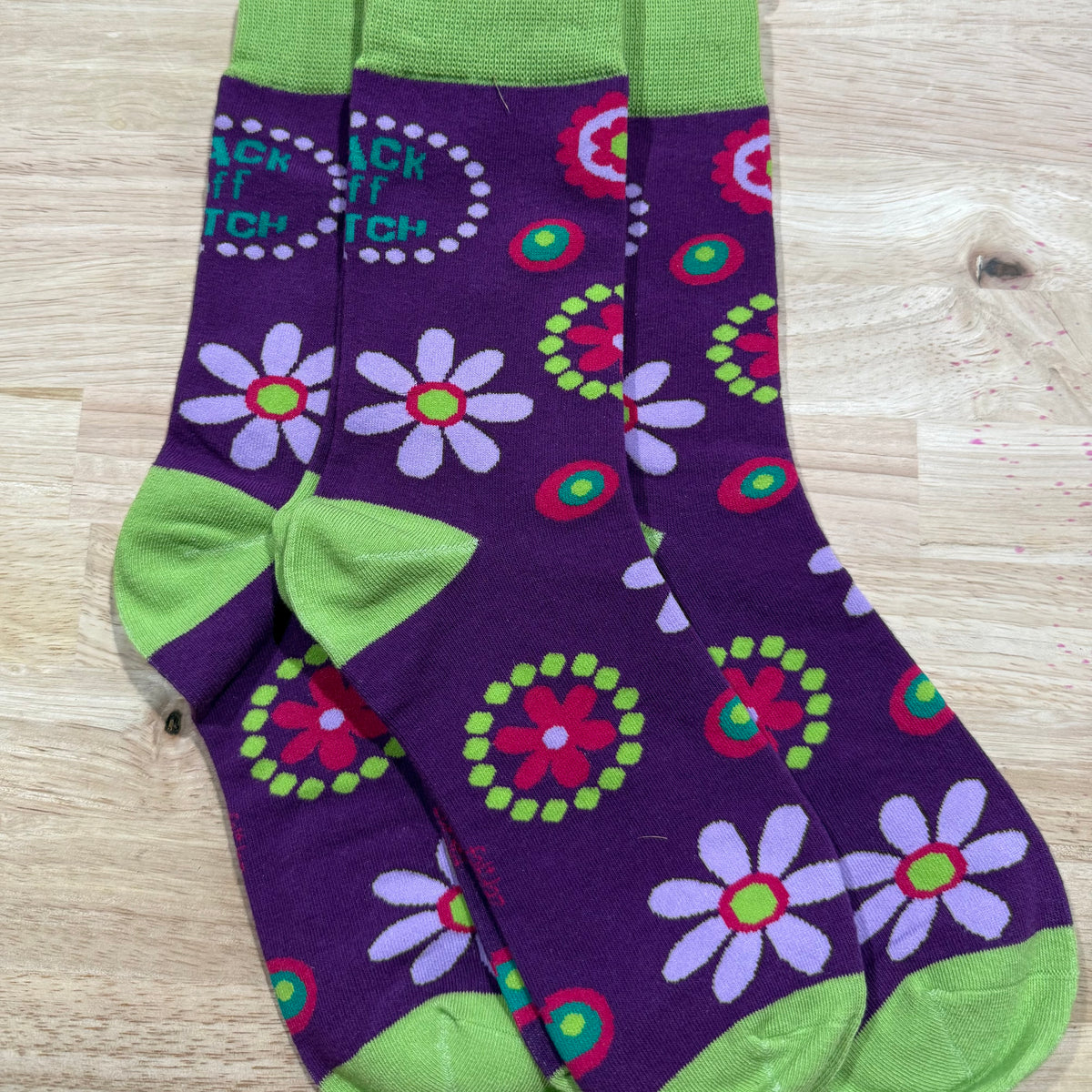 Purple adult novelty socks with green cuffs and colorful flower and circle patterns