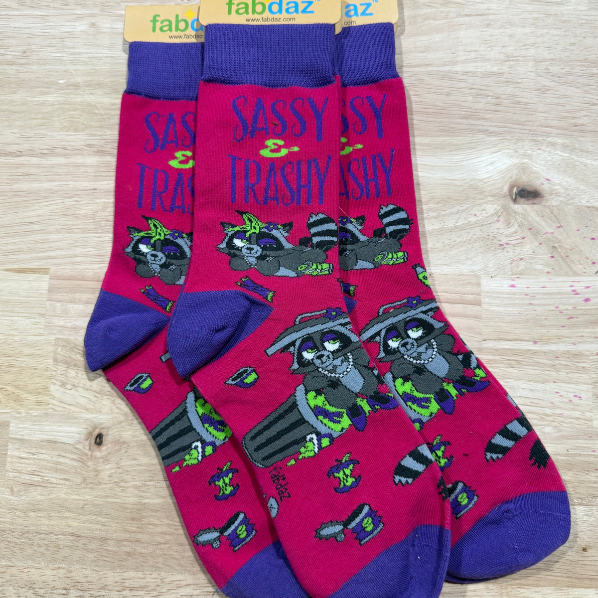 Funny socks with pink and blue cat graphic, dark toes, and text 'Sassy & Trashy'.