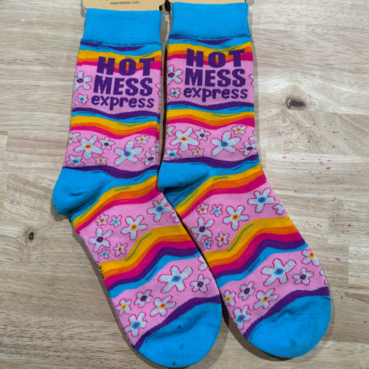 Colorful funny socks with rainbow stripes, pink flowers, and 'Hot Mess Express' print