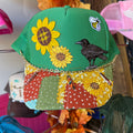 Green patchwork trucker hat with embroidered flowers and black bird front panel