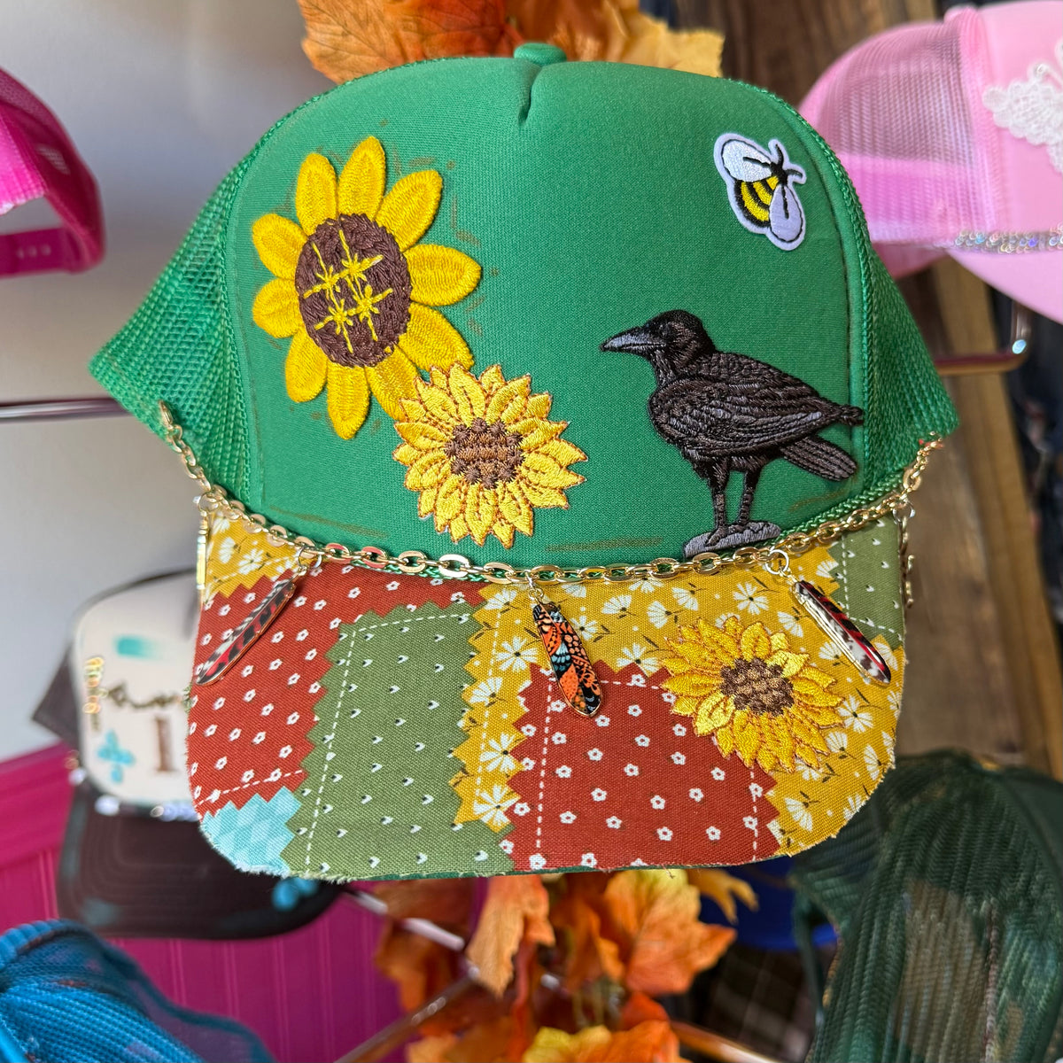 Green patchwork trucker hat with embroidered flowers and black bird front panel