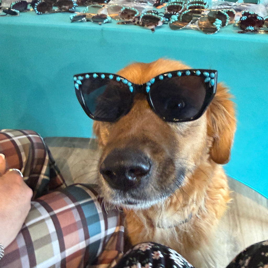 Turquoise sunglasses with black round lenses and teal beads outlining the frames