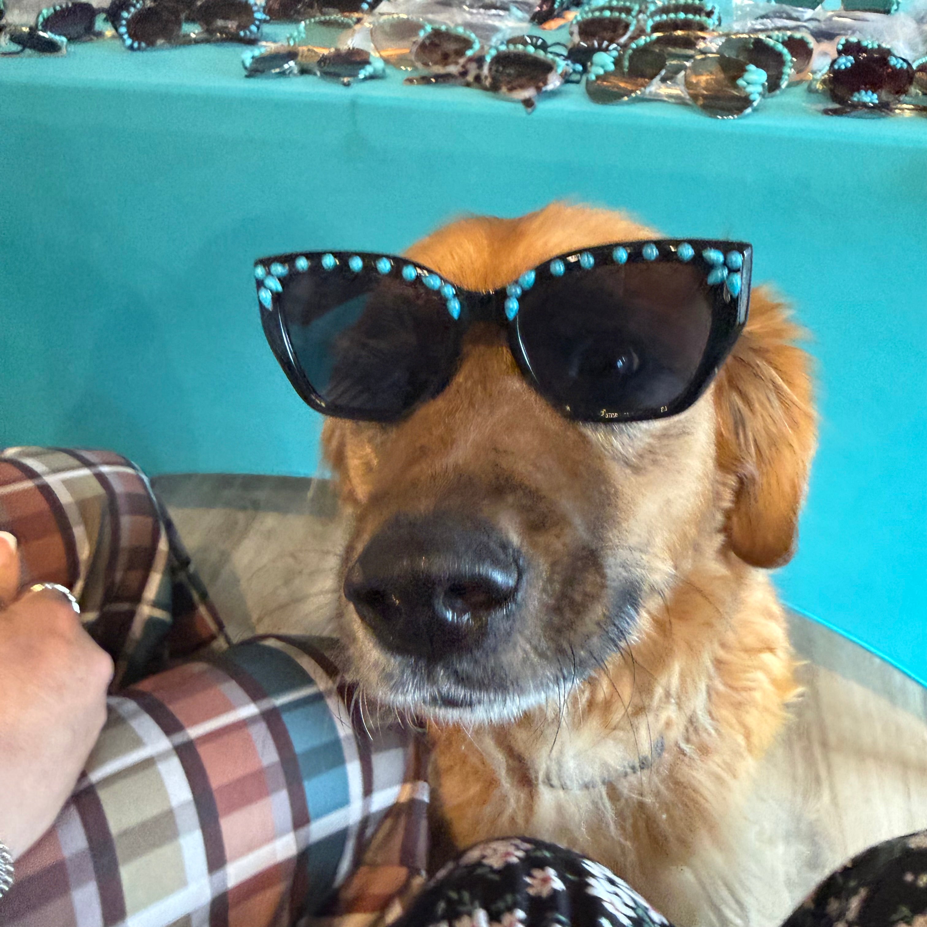 Turquoise sunglasses with black round lenses and teal beads outlining the frames