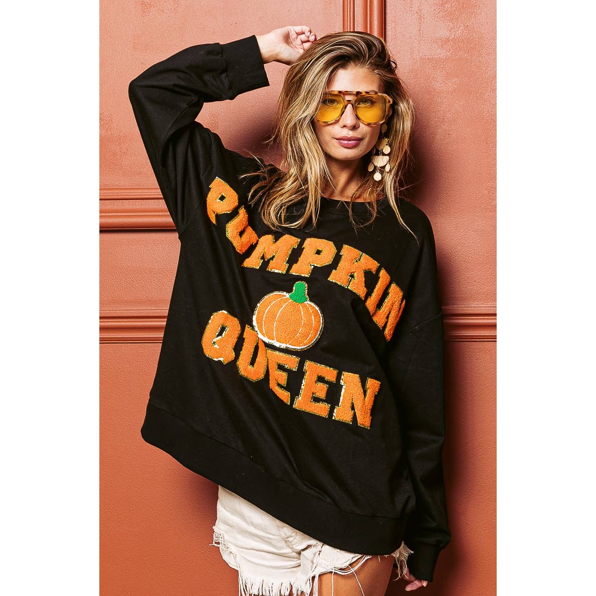 Black sweatshirt with orange "PUMPKIN QUEEN" print and pumpkin graphic, tilted