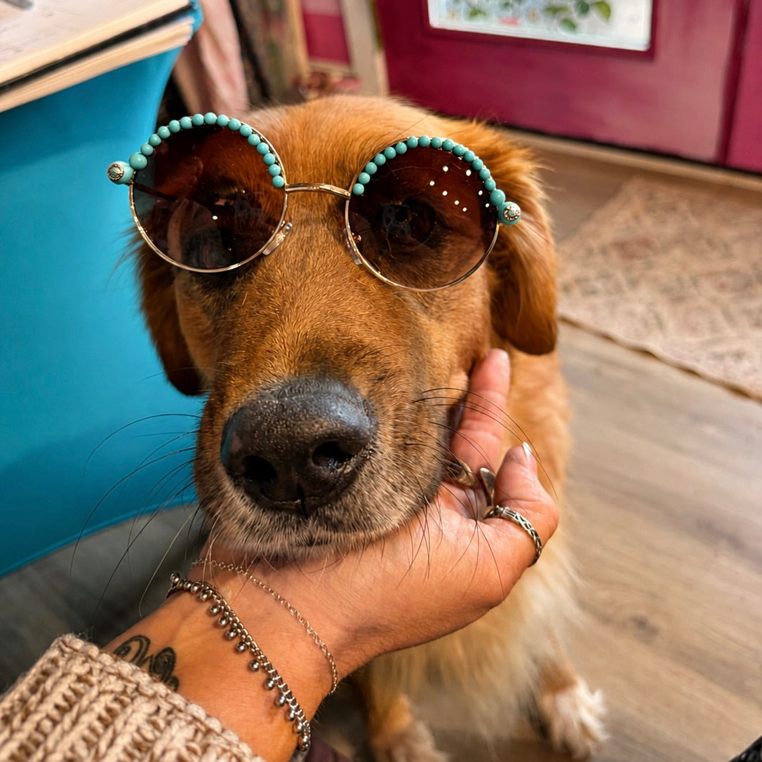 Turquoise sunglasses with dark round lenses, teal beads, and a gold-toned bridge