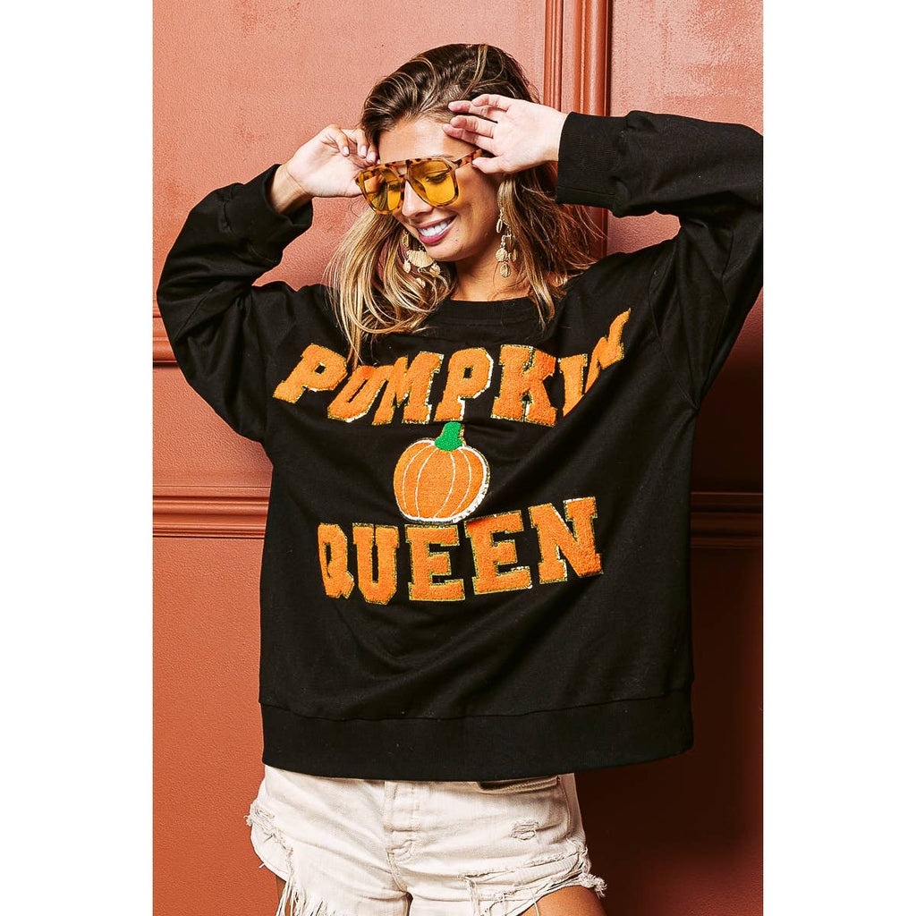 Black sweatshirt with orange "PUMPKIN QUEEN" print and pumpkin graphic, close
