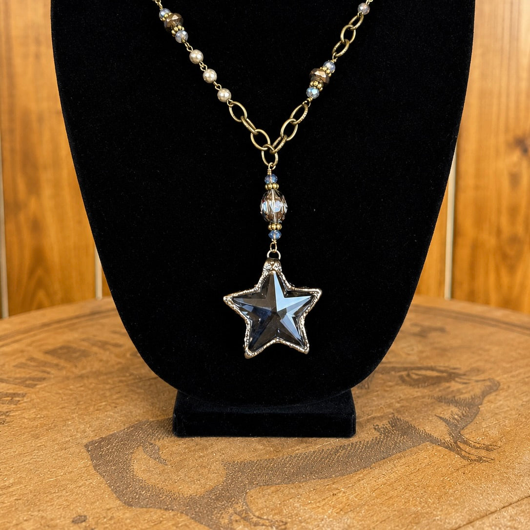Star pendant necklace close-up: gold-tone chain with blue star, small crystal drops