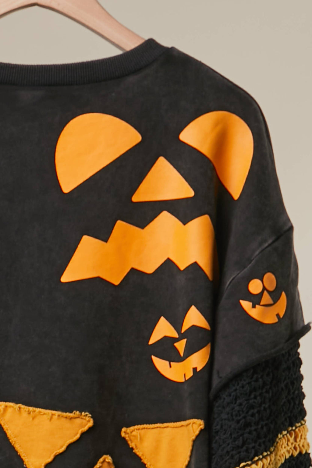 Black top with orange pumpkin face print and striped sleeve cuff